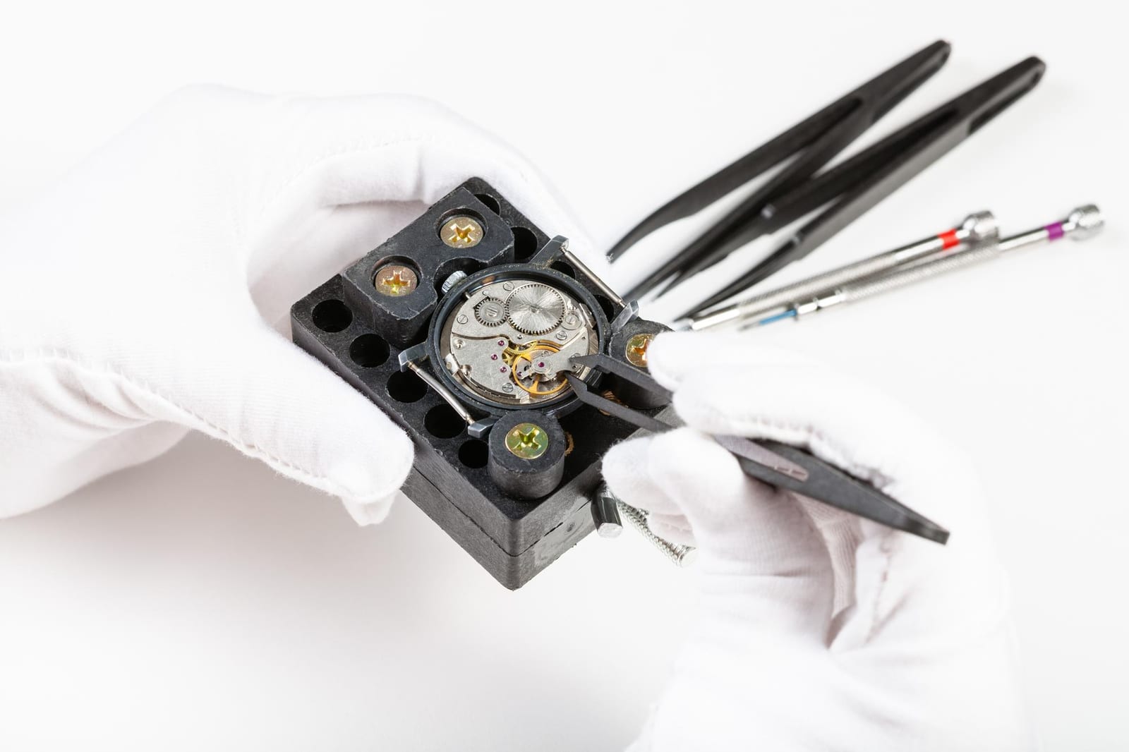 Banco da lavoro orologiero con attrezzi di precisione e un orologio meccanico aperto